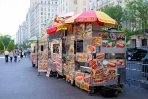 Puestos icónicos de comida en Wall Street con hot dogs y halal en el distrito financiero de Nueva York durante la hora del almuerzo.