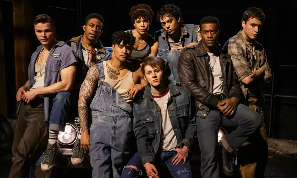 Escena inspirada en The Outsiders Broadway con ambiente teatral moderno y público en Nueva York