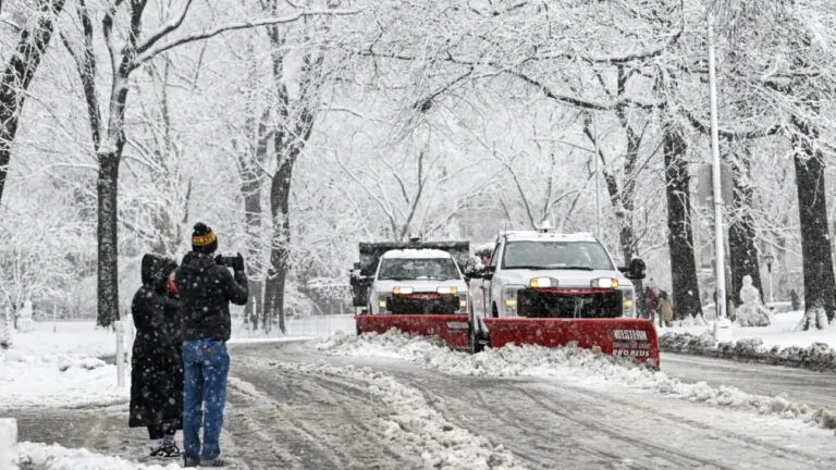 Residente retira nieve de una banqueta para evitar multas por nieve en Nueva York y mantener seguro el paso peatonal.